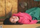 A young girl laying on a tatami mat in a room.