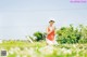 A woman in a red bathing suit sitting in a field of flowers.