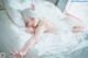 A woman laying on a bed with white sheets and pillows.