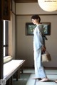 A woman in a blue and white kimono standing in a room.