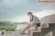 A woman sitting on the steps of a concrete building.