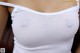 A close up of a woman wearing a white tank top.